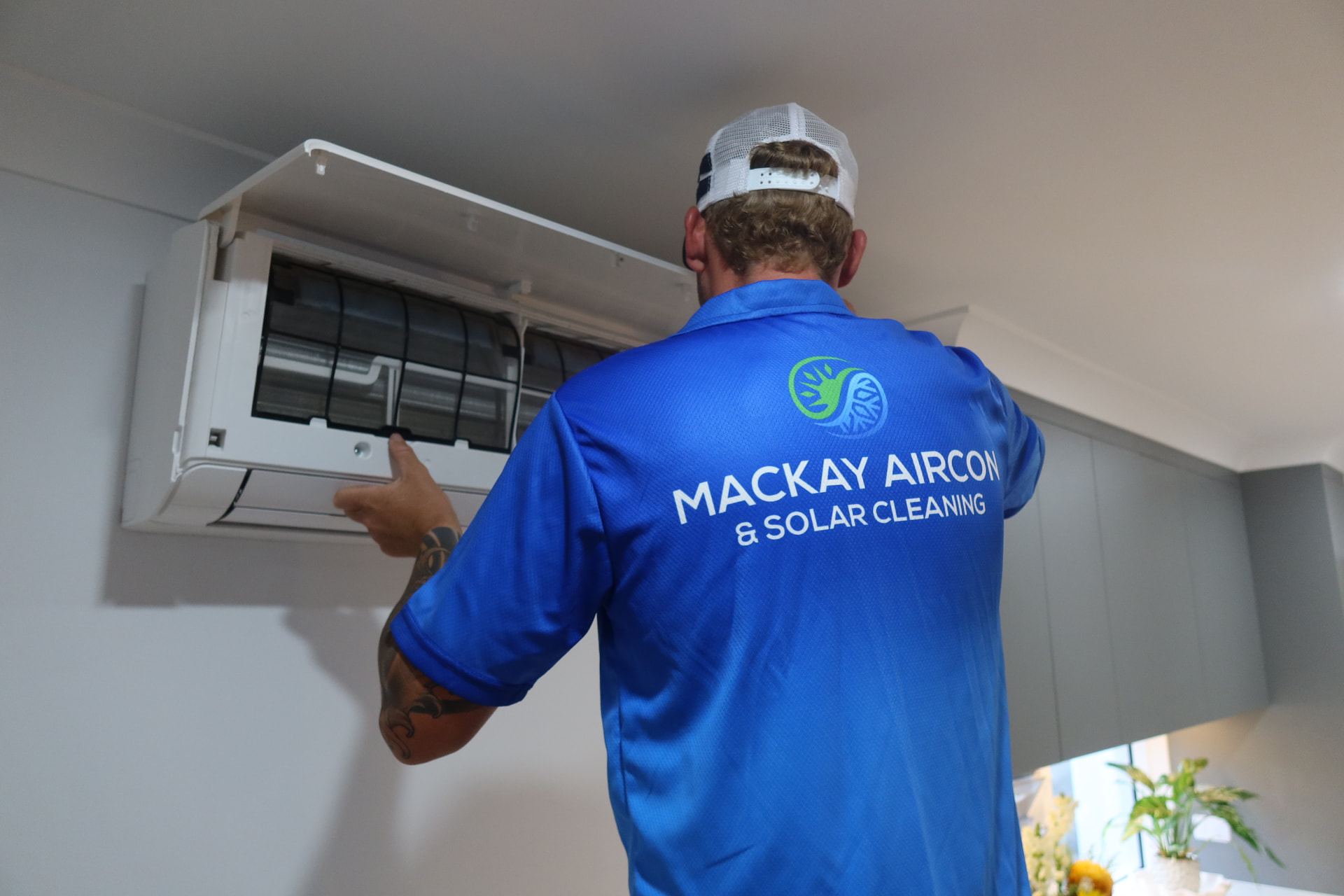 Technician opening a split system air conditioner in a Mackay home
