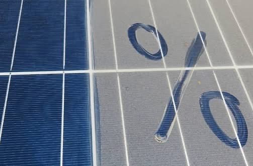 Percentage sign drawn in the dirt on a solar panel next to a clean panel