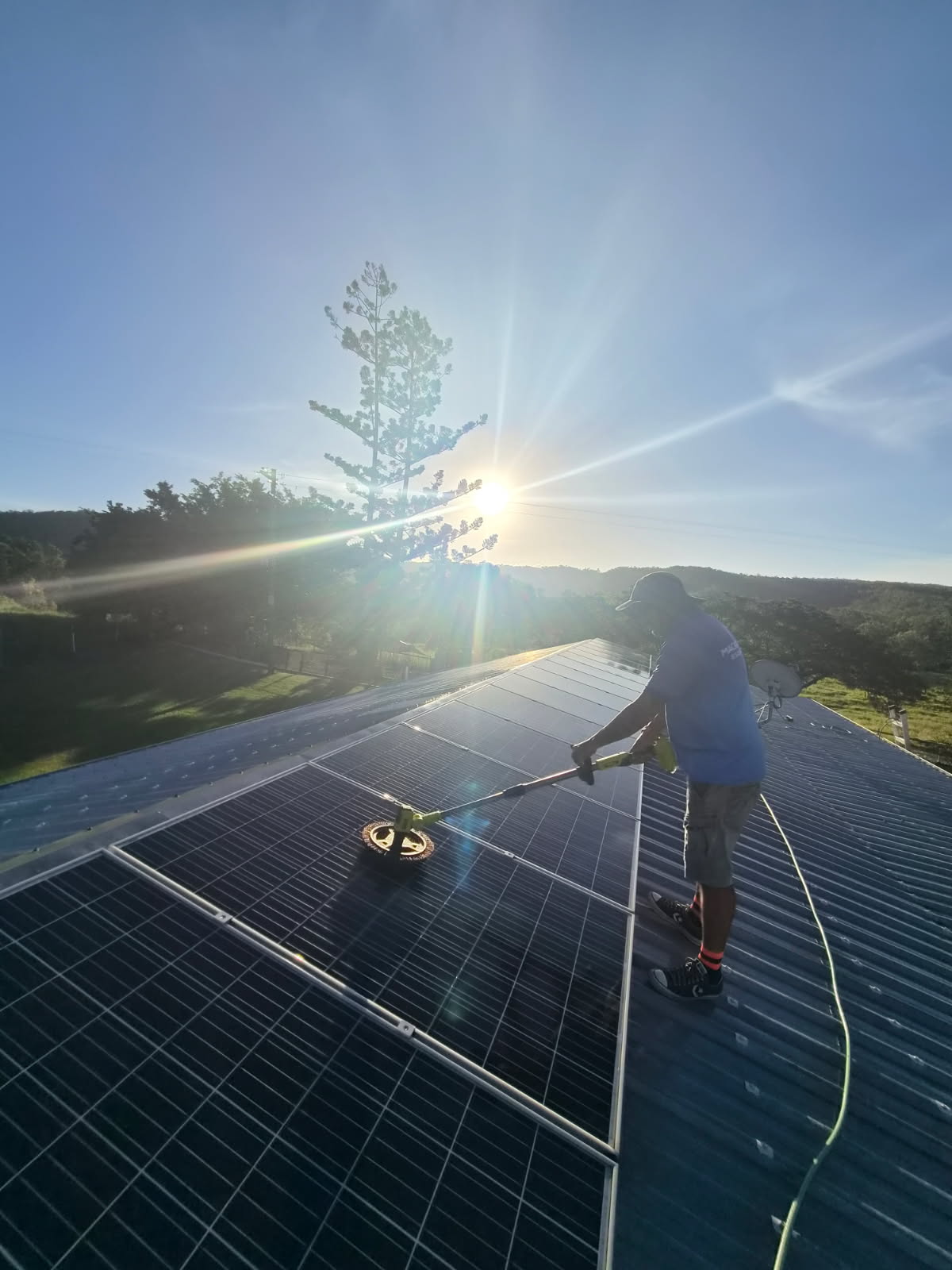 Solar panels being washed at sunrise on a Mackay roof