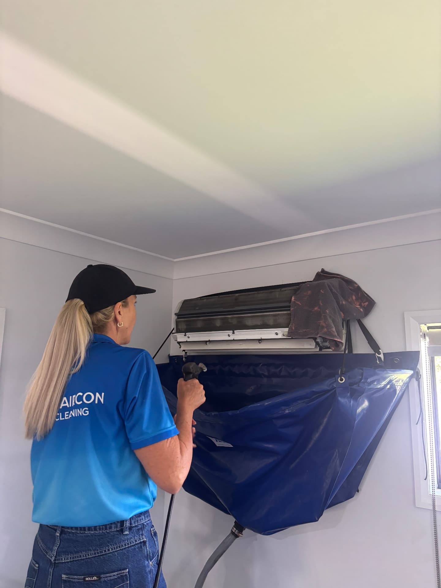A Mackay Aircon & Solar Cleaning technician cleaning an air conditioner in a customer's home
