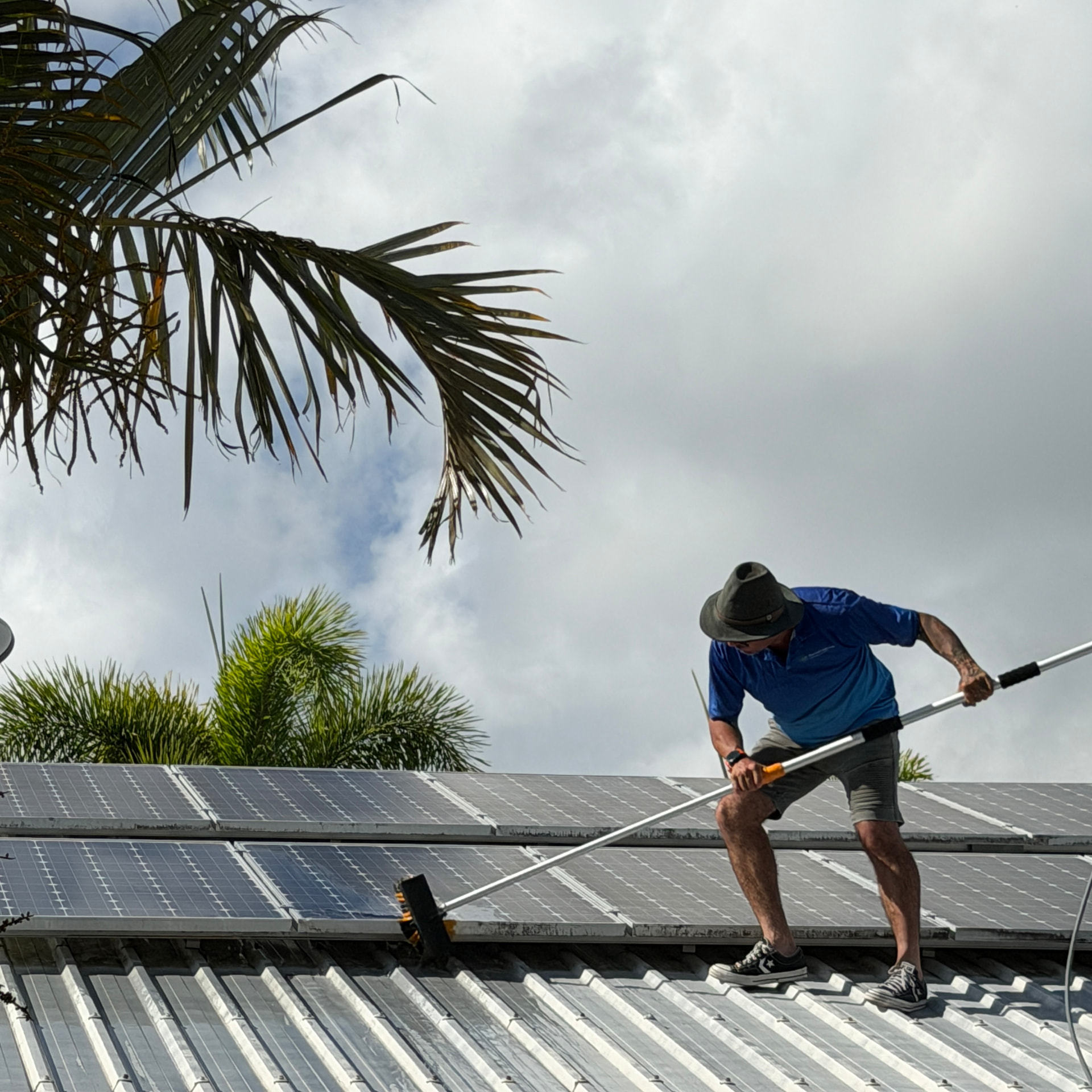 Technician brushing rooftop solar panels clean
