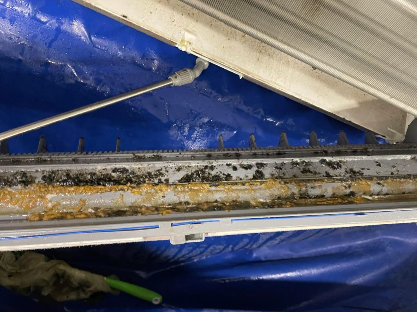 Dirty drain tray inside an air conditioner being flushed out