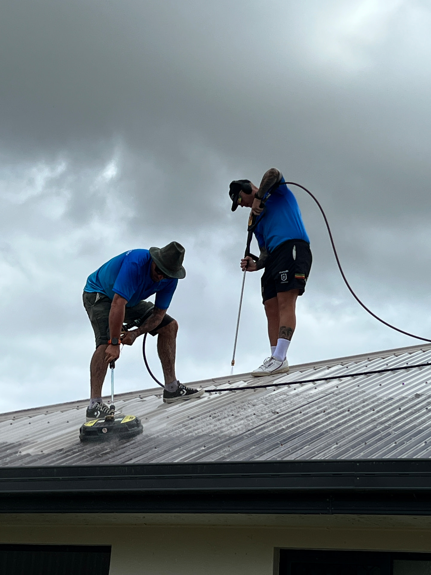 Technicians pressure cleaning a metal roof in Mackay